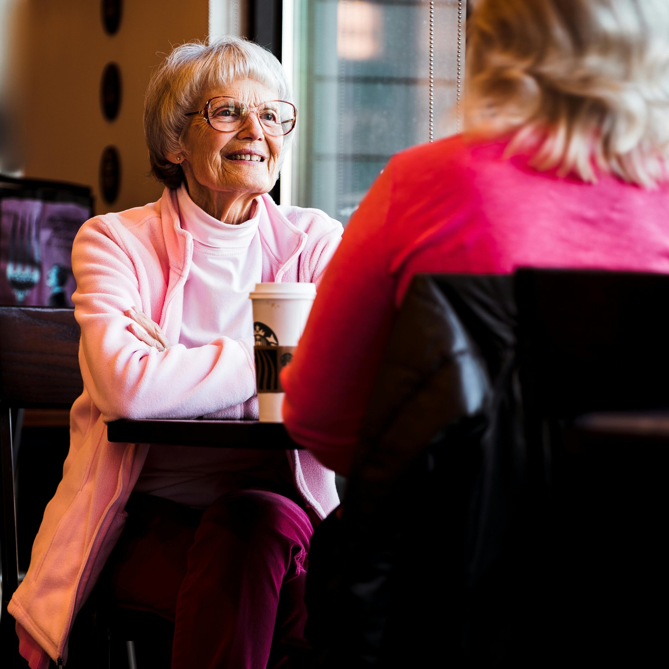 Two senior women enjoying a warm conversation over coffee in a cozy café.